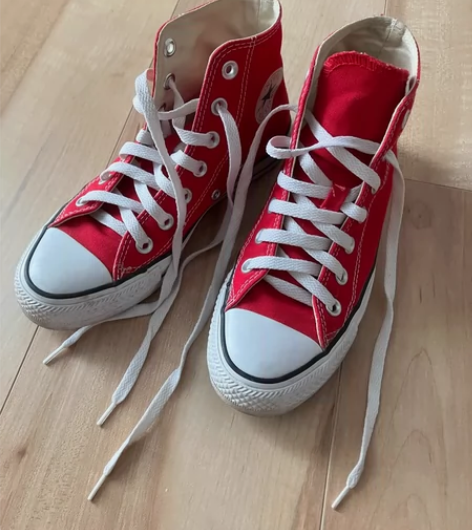 出一双红色的Converse帆布鞋，鞋底略...