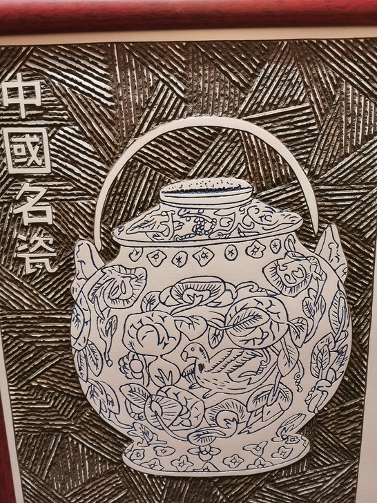 此为中国独有的瓷板雕刻画,雕刻一个青花瓷罐...